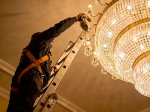 limpiar una lámpara de araña en un techo alto